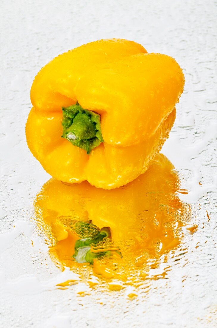 A yellow pepper on a wet mirror