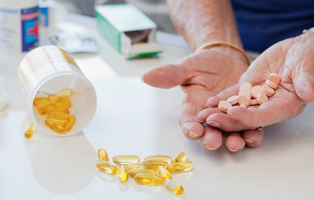 Ältere Frau hält Tabletten in der Hand