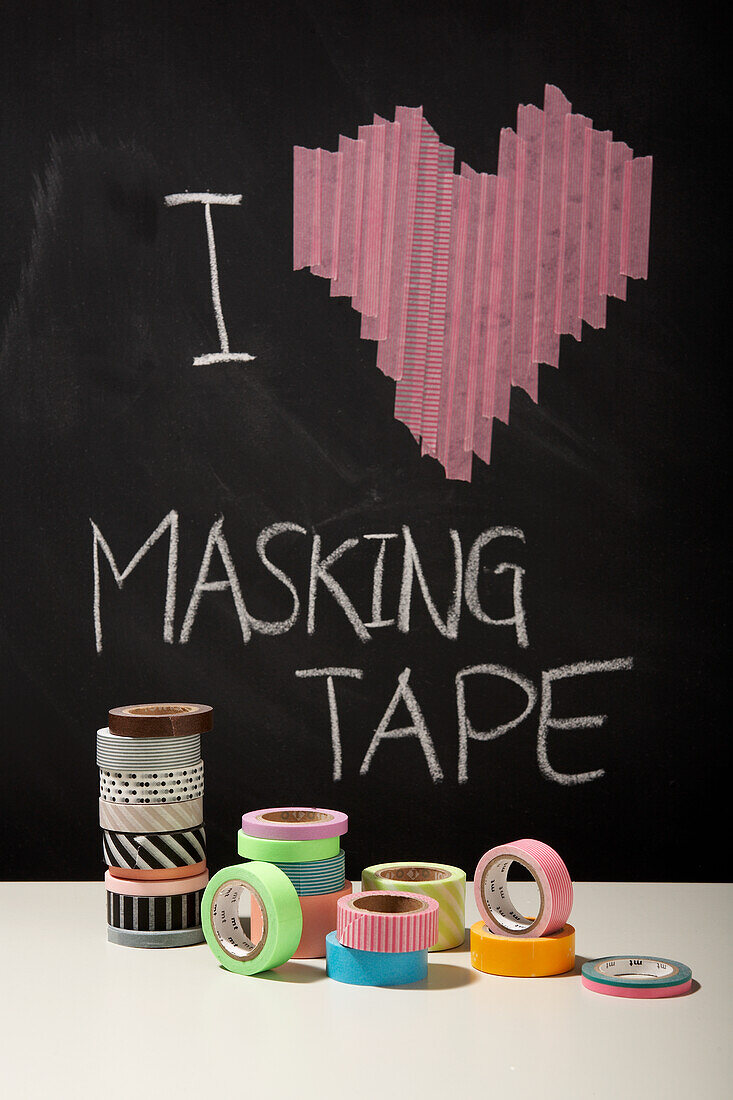 Bunte Masking-Tape-Rollen vor Tafel mit Herz-Motiv und Schriftzug