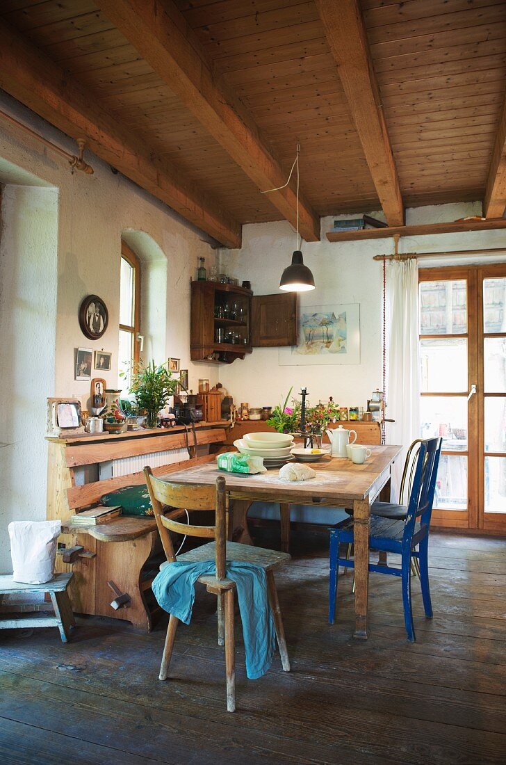 Rustic kitchen with wooden ceiling, dining table, wooden chairs and corner bench