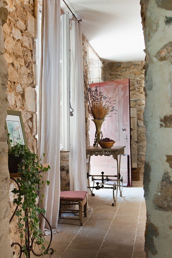Delicate, French, metal furniture against rustic stone walls in Provençal country house