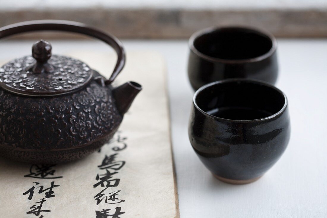 A teapot and two black tea bowls
