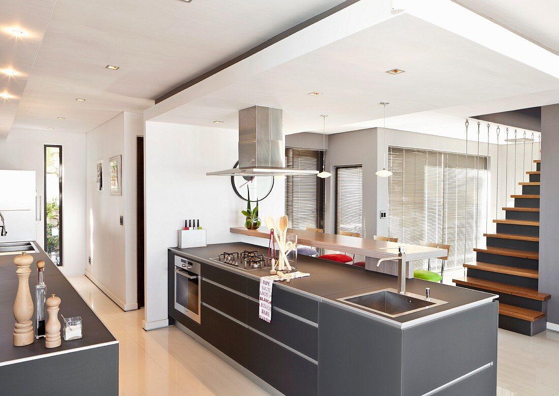 Freistehende Küchentheke mit grauen Oberflächen unter abgehängter Decke in modernem, offenem Wohnraum gegenüber Treppenaufgang