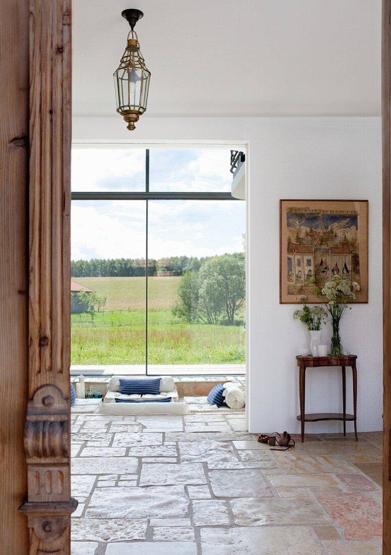 View into living area of detached house with rustic stone floor and large panoramic windows