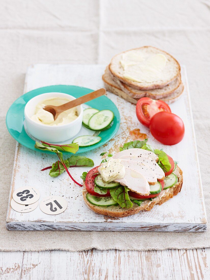 Slices of bread topped with cucumber, tomatoes, lettuce and turkey breast