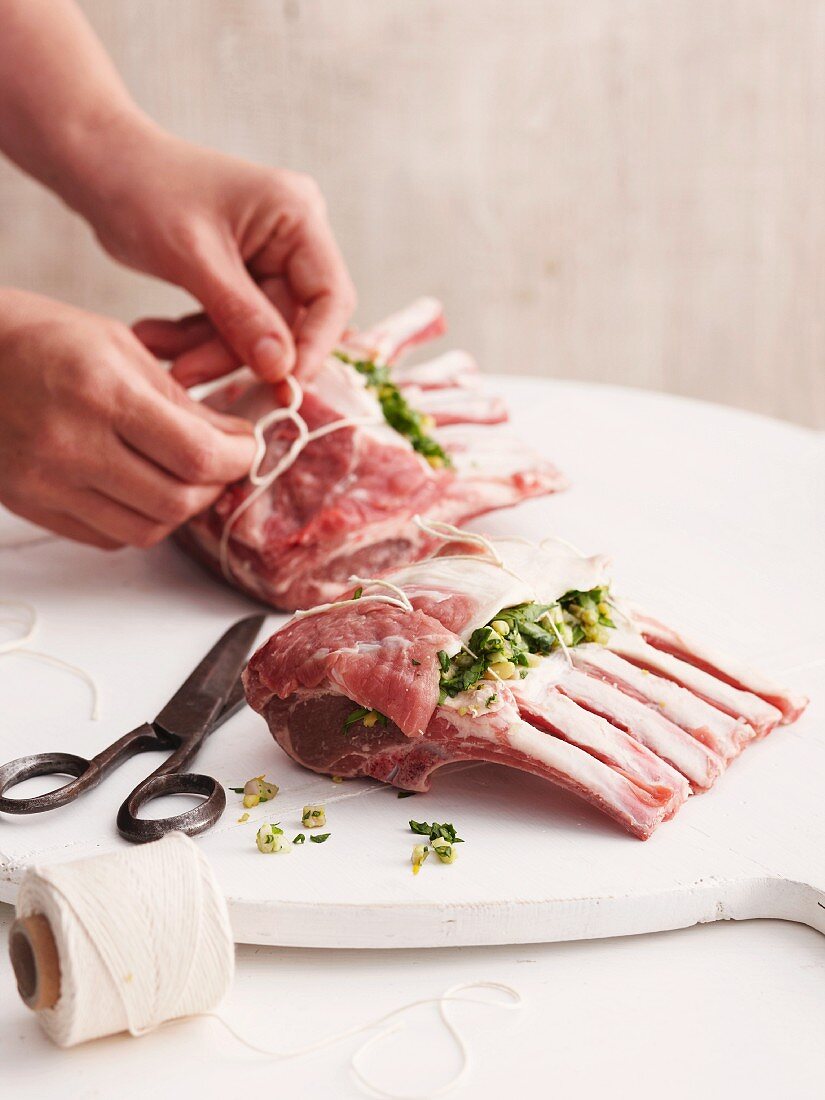 Stuffed lamb loin rack joints being tied with twine