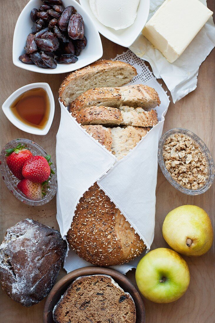 Stillleben mit Brot, Obst, Lebkuchen, Sirup & Datteln (Aufsicht)