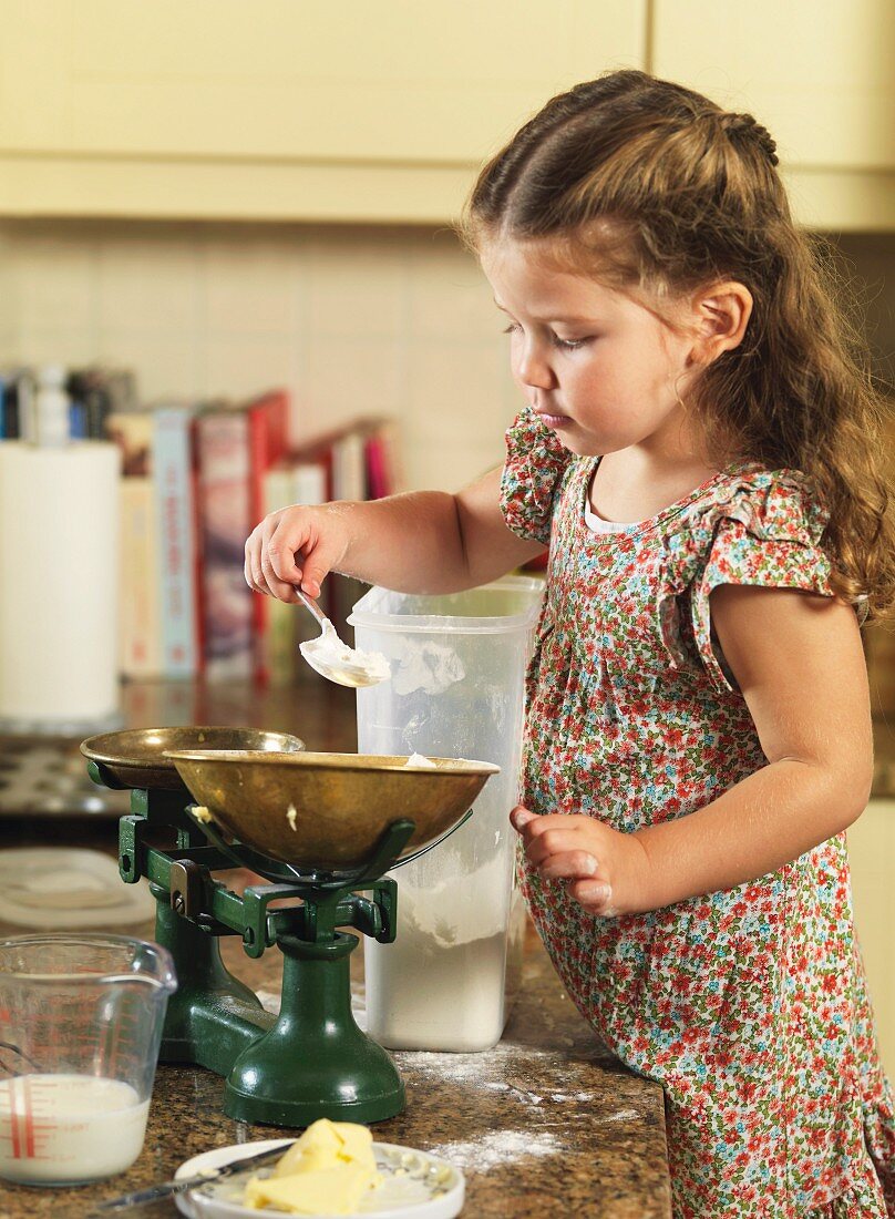 Kleines Mädchen beim Mehl abwiegen