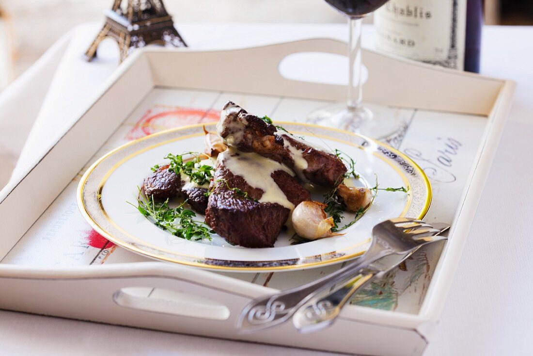 A plate of Chateaubriand and Bearnaise sauce on a tray with cutlery