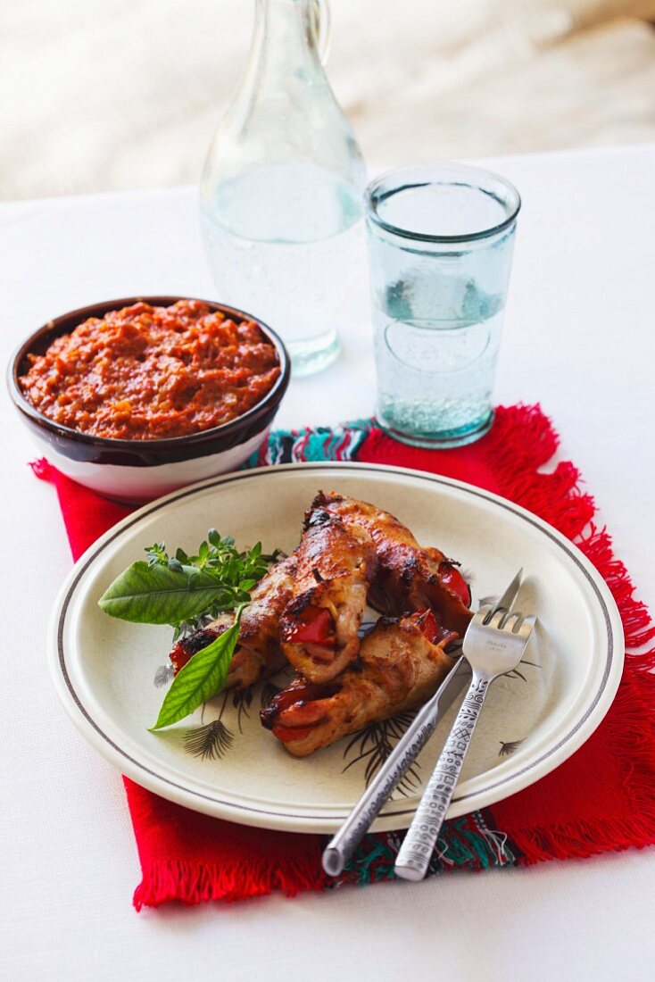 Gegrillte Schweinerouladen mit scharfem Dip im Hintergrund