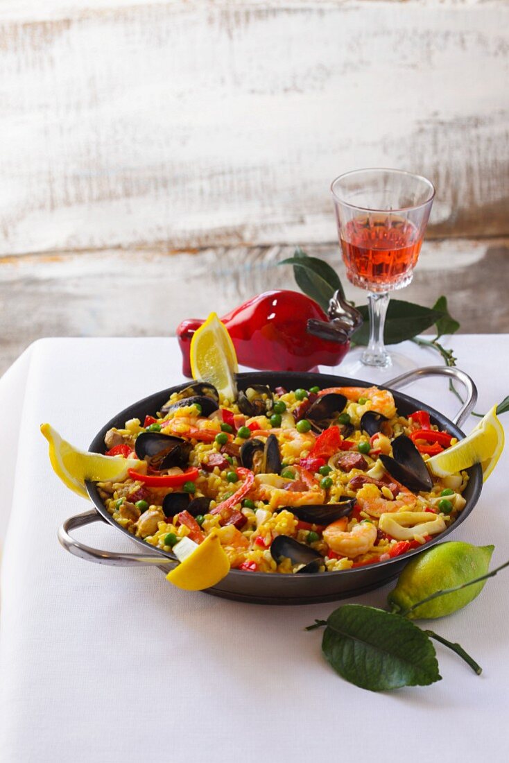 A pan of mixed paella and a glass of wine