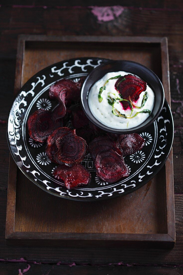 Beetroot chips with a quark dip on a black patterned plate