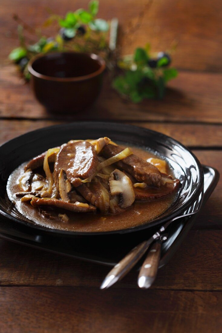 Pork fillet with mushrooms and onions on a black plate