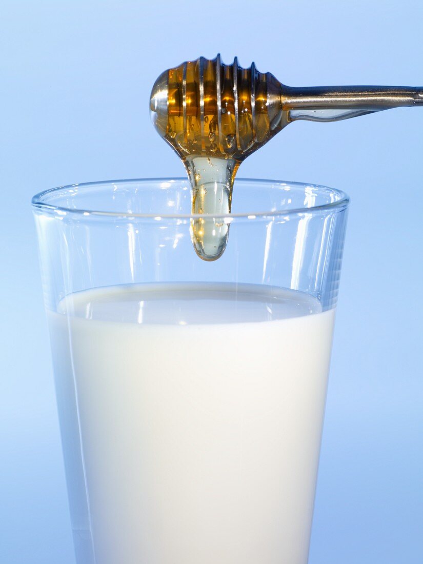 Honey dripping into a glass of milk