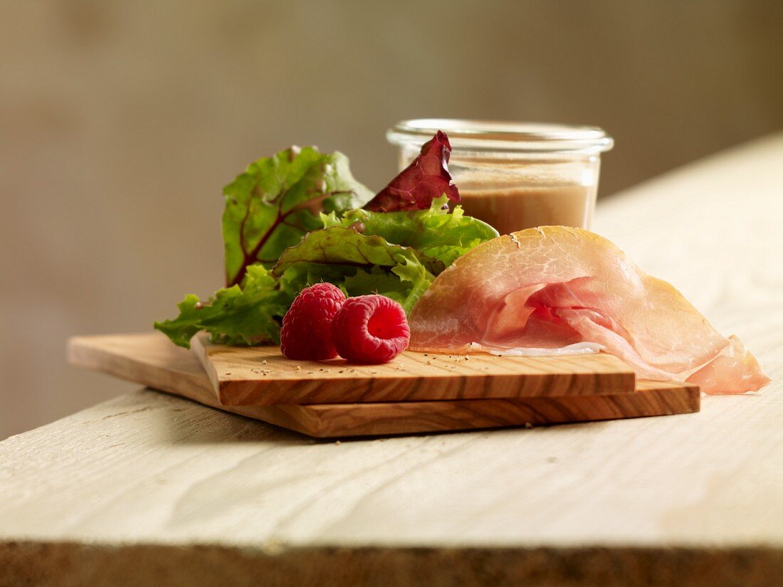 Salad ingredients: lettuce, Parma ham, raspberries and dressing