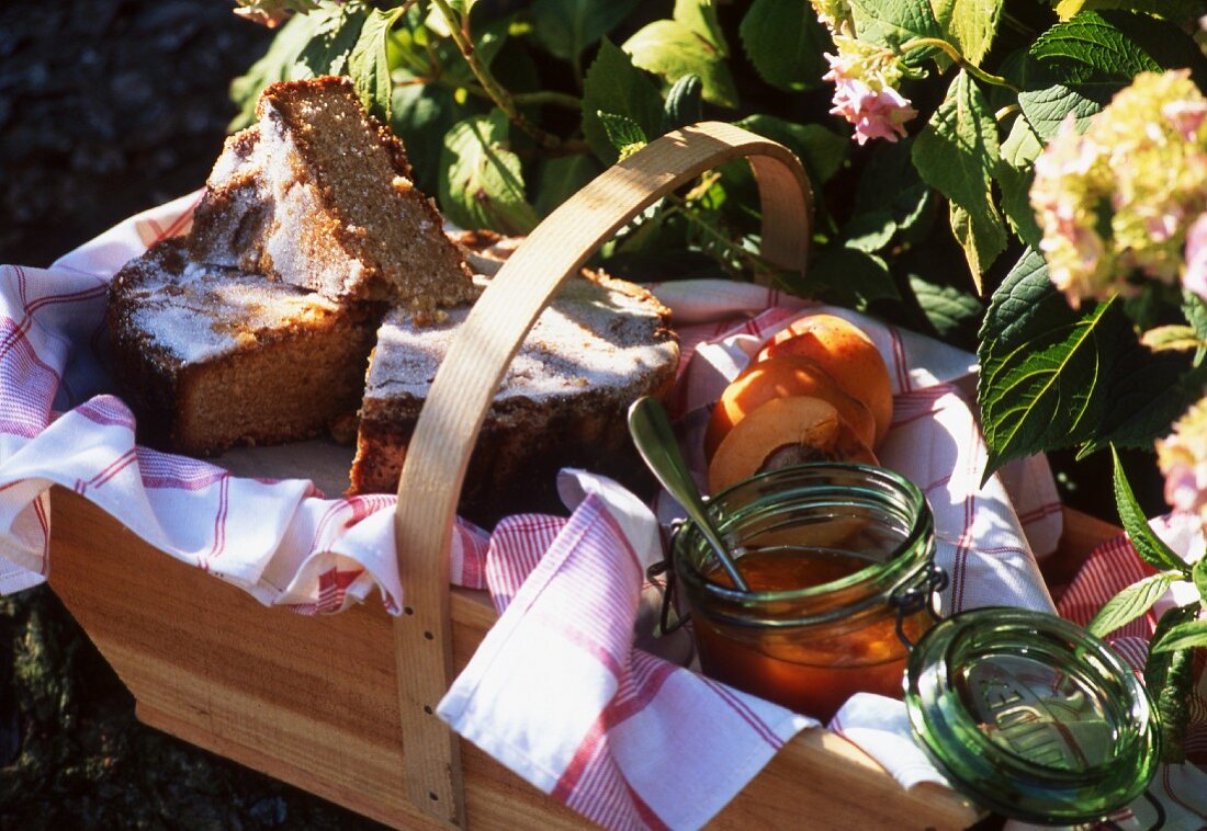 Pfirsichmarmelade und Kuchen im Holzkorb