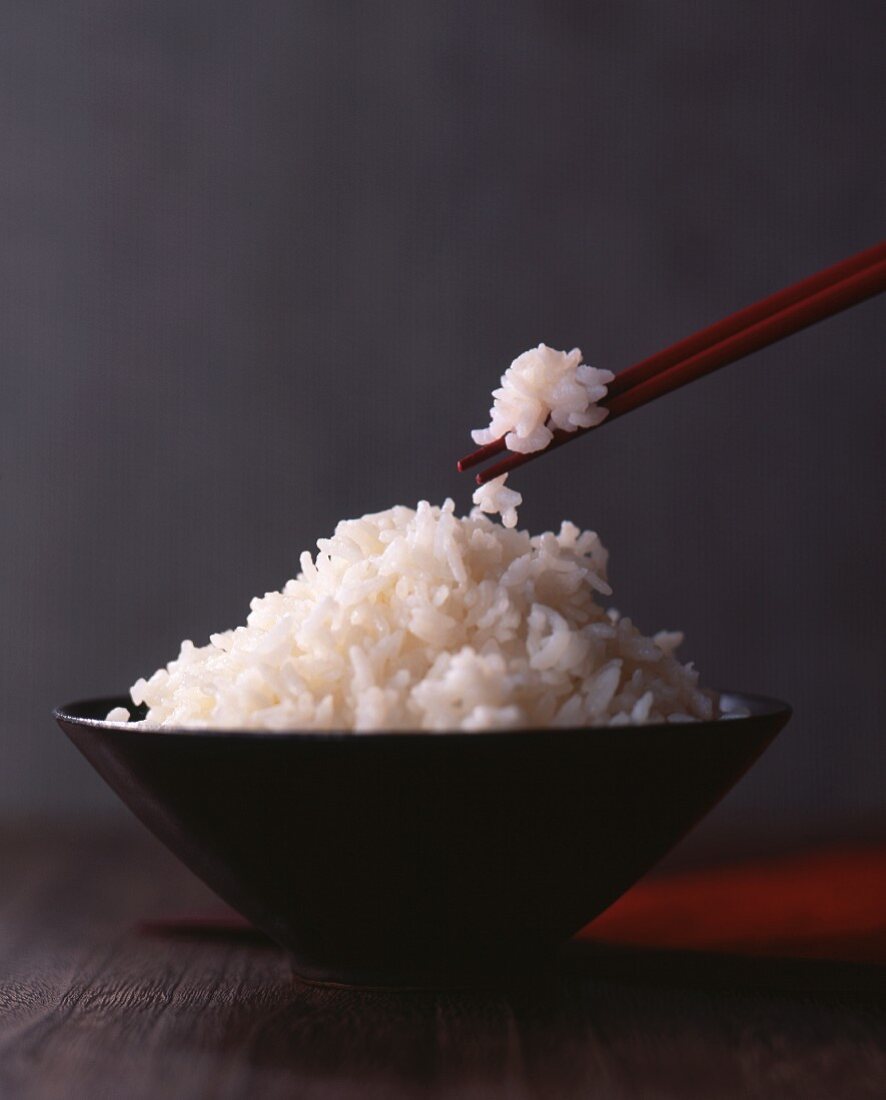 Gekochter Reis in Schale und auf Essstäbchen