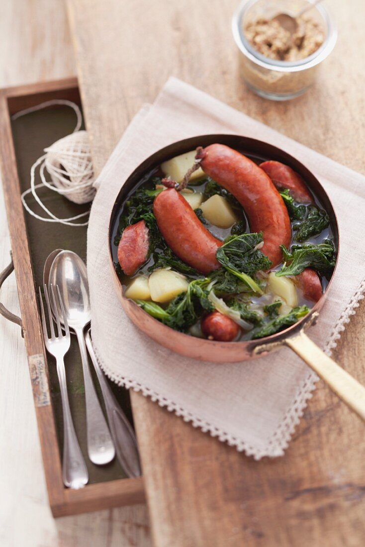 Green cabbage stew with pinkel sausage in a saucepan, seen from above