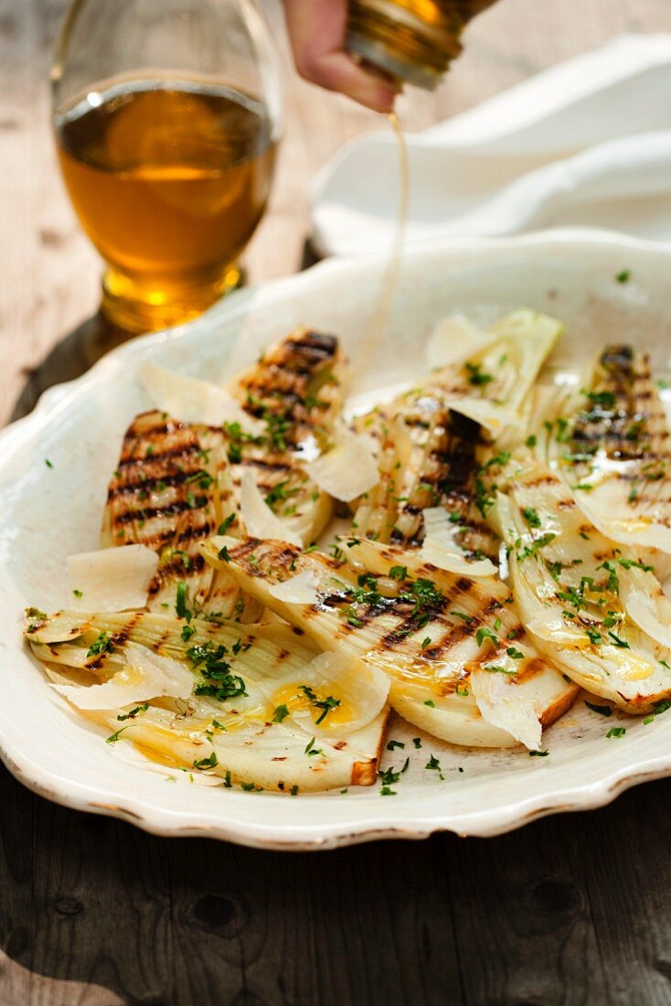 Drizzling Olive Oil Over Grilled Fennel with Fresh Herbs