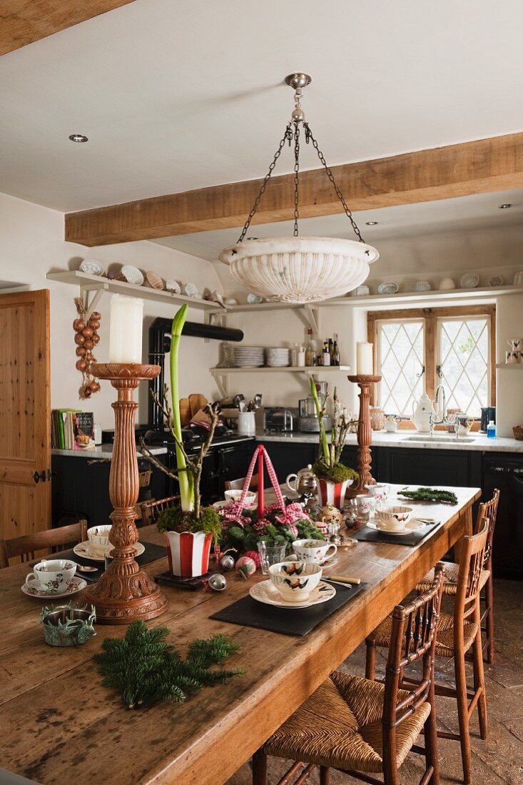 Festively set table in rustic, English country-house kitchen