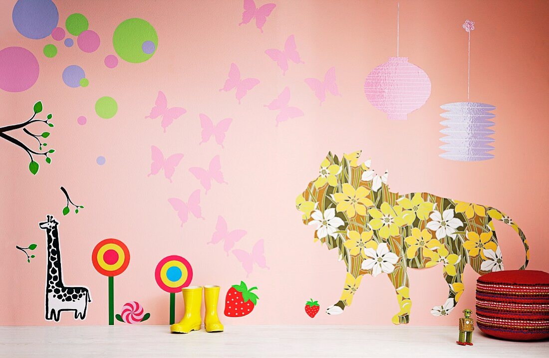 Wellington boots and pouffe in front of cheerful wall design in child's bedroom featuring floral lion, butterflies and sweets