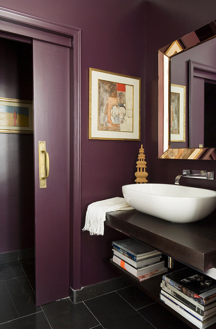 Modern washstand with white basin on wooden counter in purple-painted bathroom with open sliding door