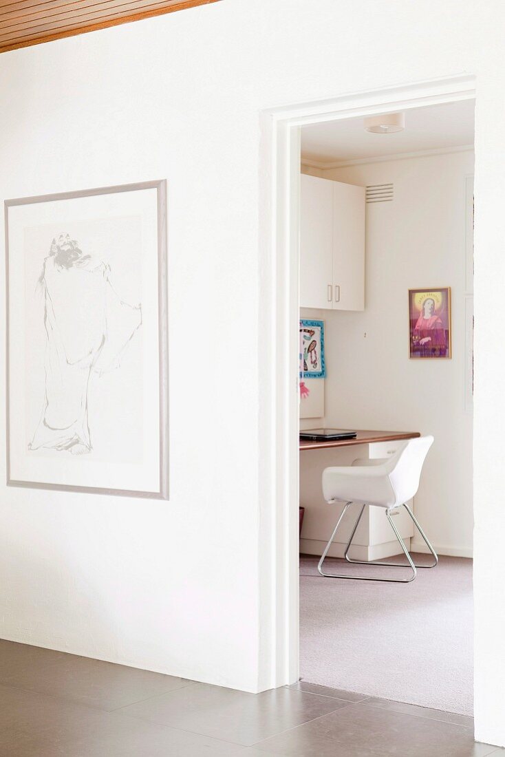 Bright study with a wall cupboard and a large work surface; a picture of a saint on the wall