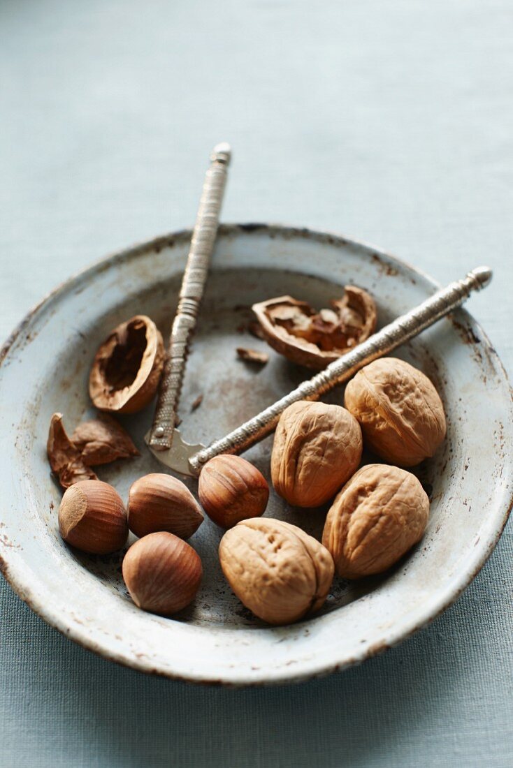 Walnuts and hazelnuts, some cracked, with a nutcracker