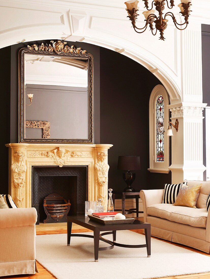 Mirror on ornately carved mantelpiece behind classic lounge area with two sofas