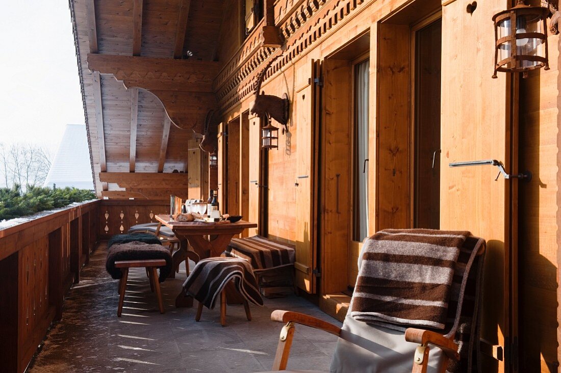 Liegestuhl mit Tagesdecke und Sitzplatz auf Balkon eines Chalets