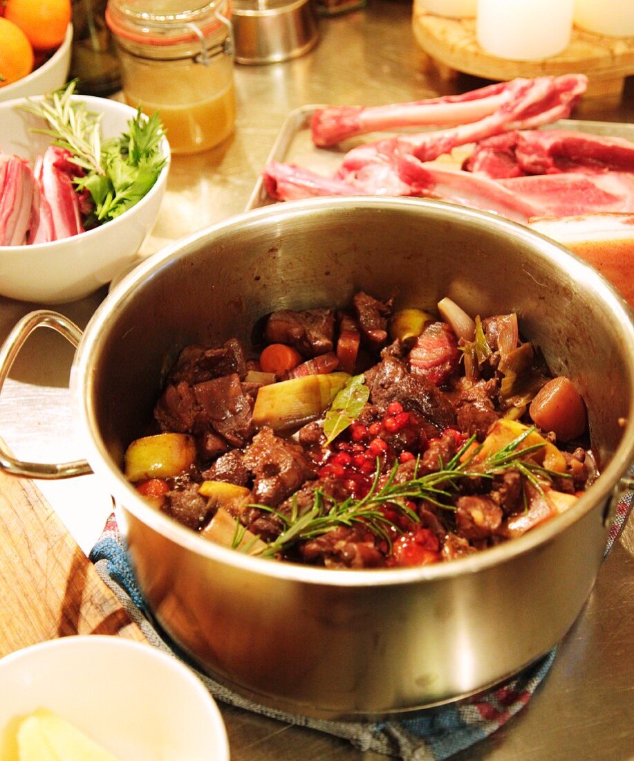 Braised venison ragout in a pot with a sprig of rosemary