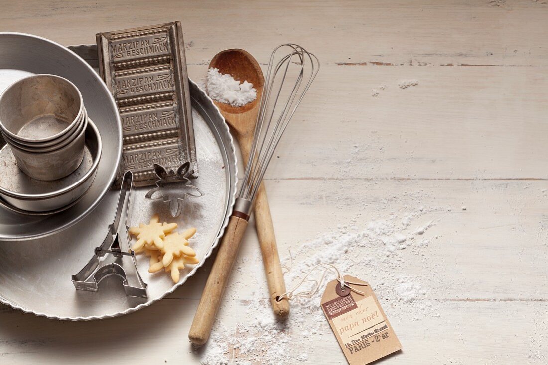 An arrangement of baking tins, a wooden spoon and a whisk