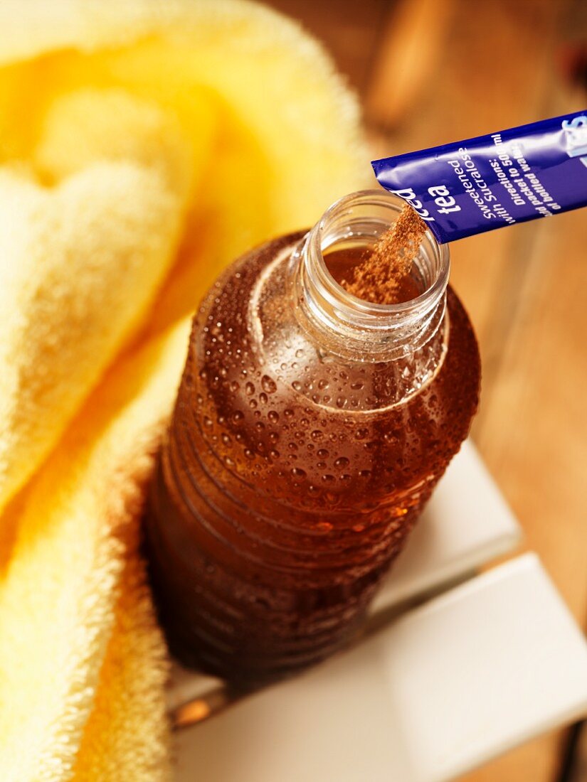 Iced tea powder being poured into a bottle