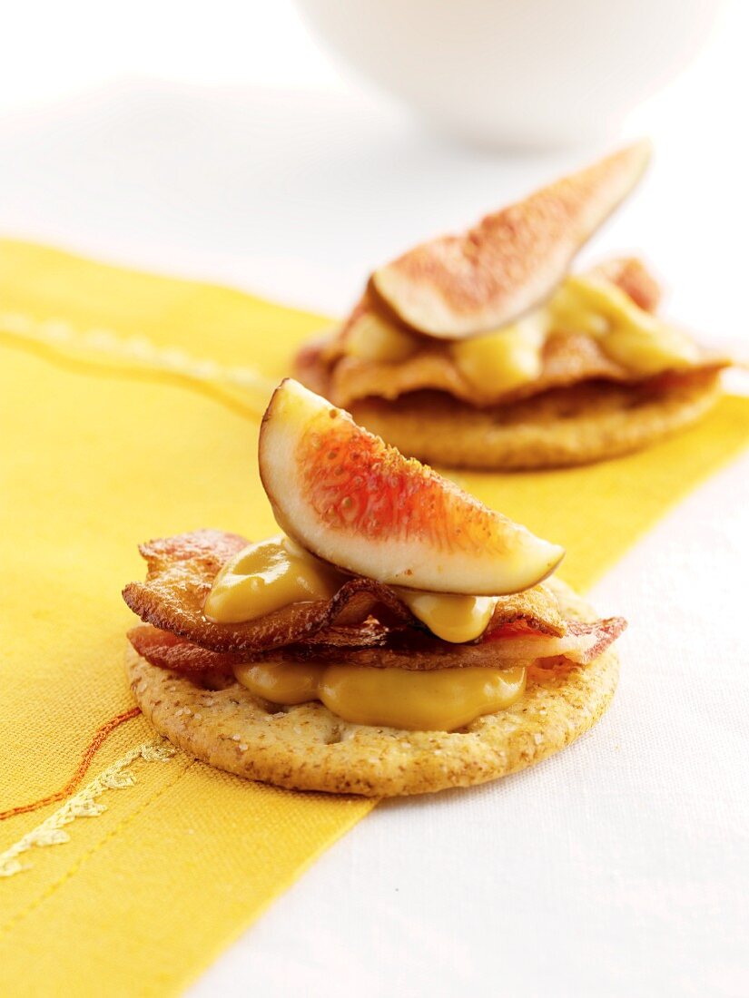 Round crackers topped with honey-mustard sauce, bacon and figs