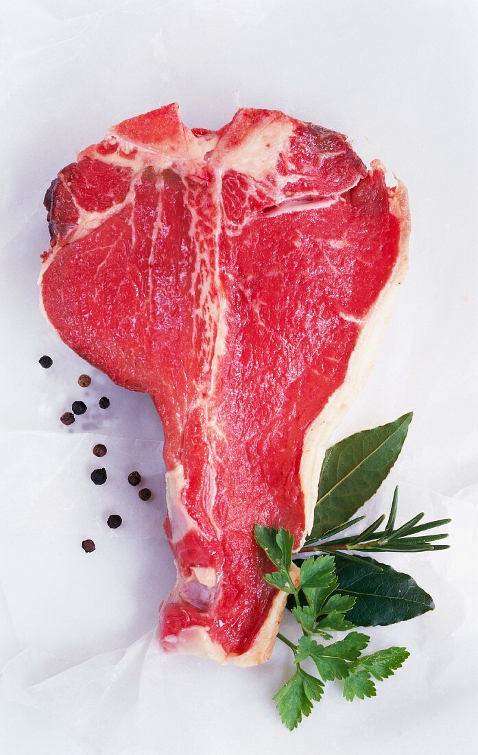 A T-bone steak, peppercorns and herbs