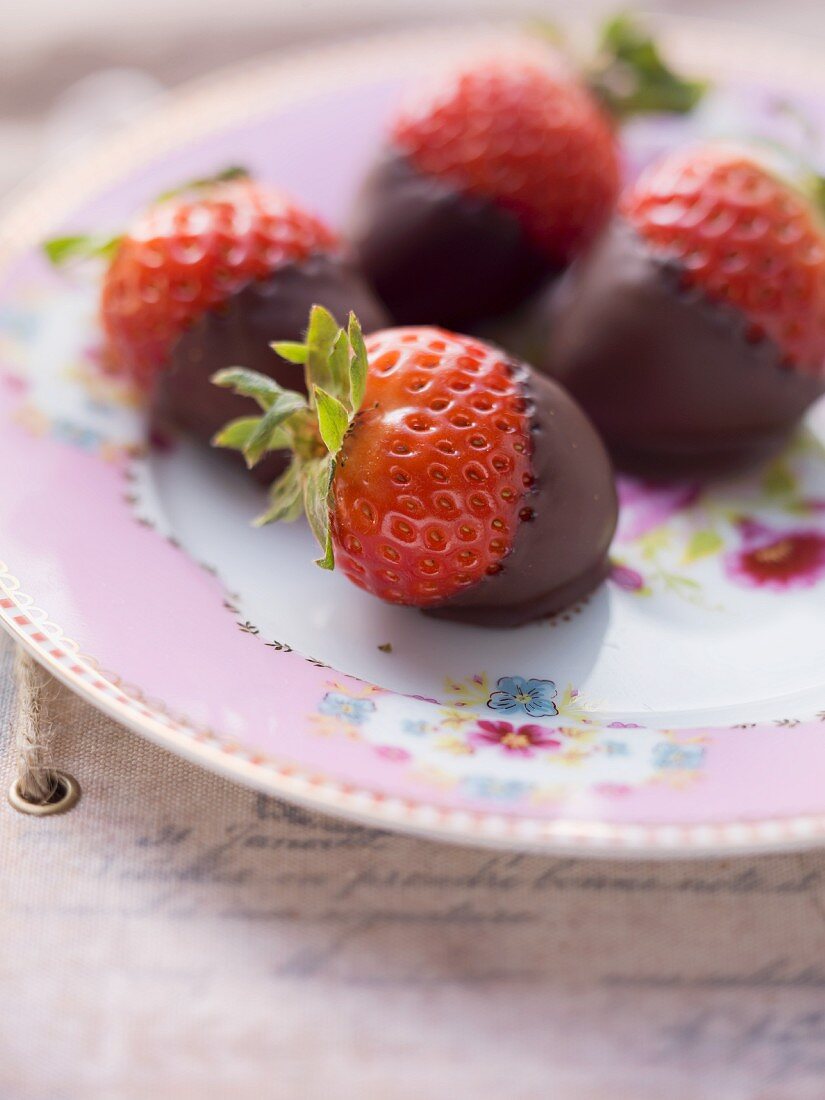 Chocolate strawberries on a pink, floral-patterned plate