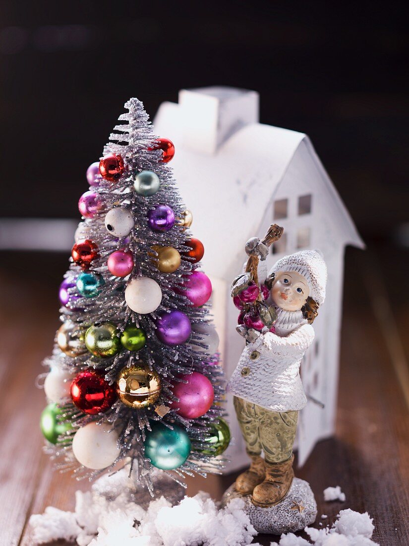 Paper house, porcelain figurine and artificial fir tree