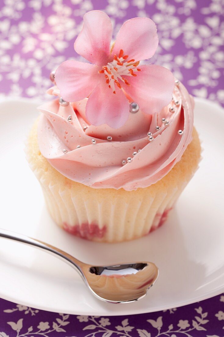 A cupcake garnished with a pink flower