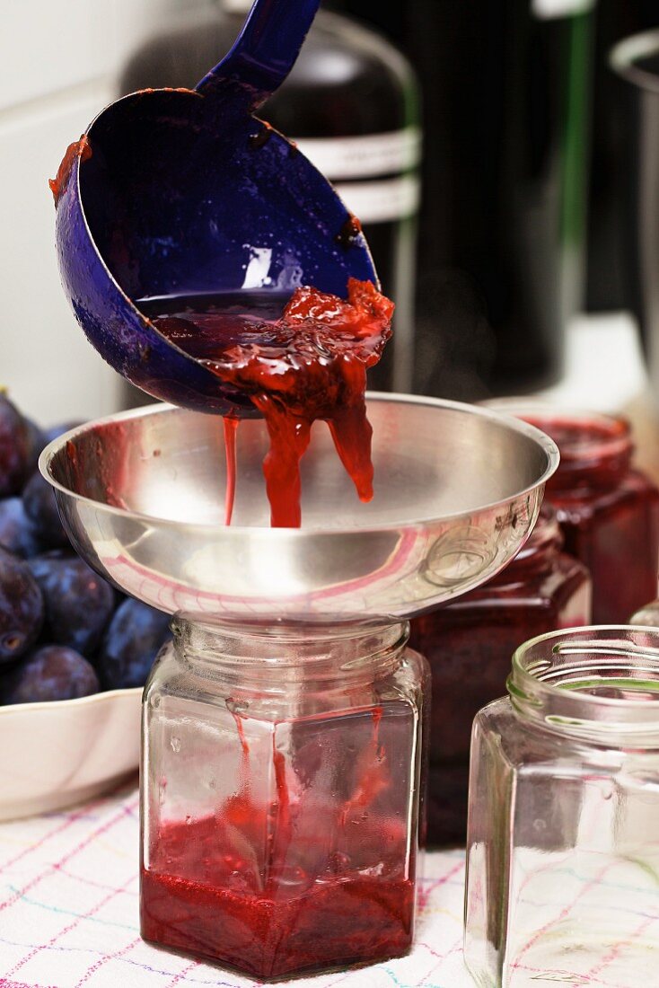 Homemade damson jam being transferred to glasses