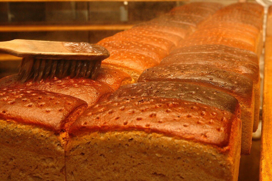 Brown bread in an oven being brushed with water