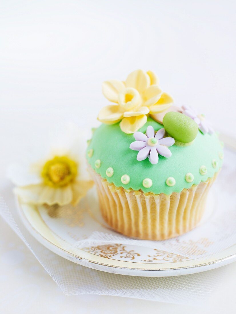 A cupcake decorated with green frosting and marzipan decorations