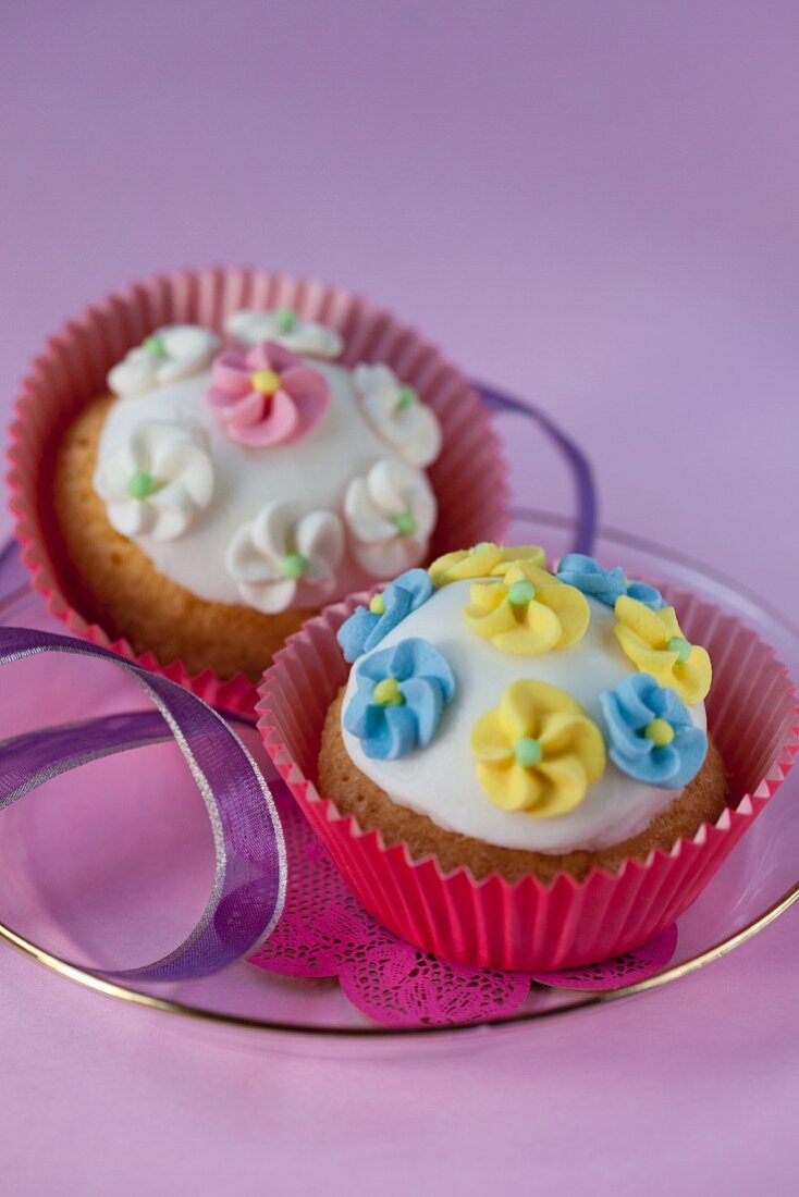 Two cupcakes with icing and sugar flowers