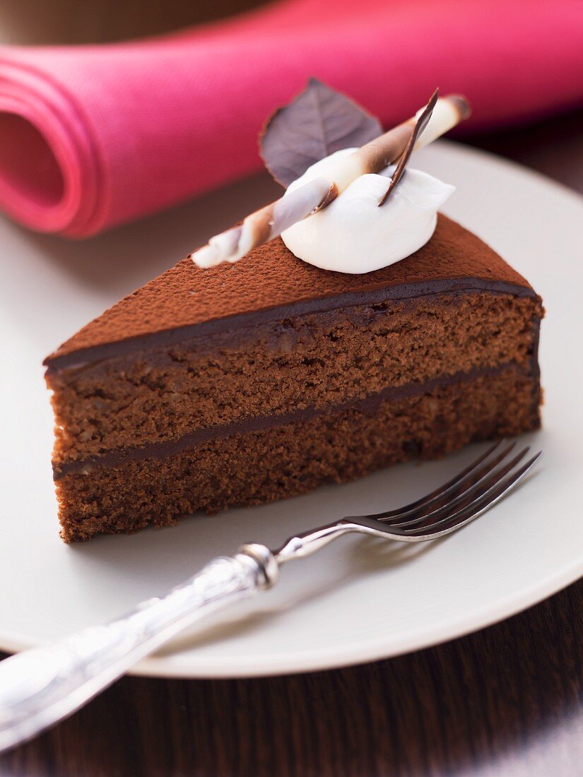 A slice of chocolate cake with a dollop of cream