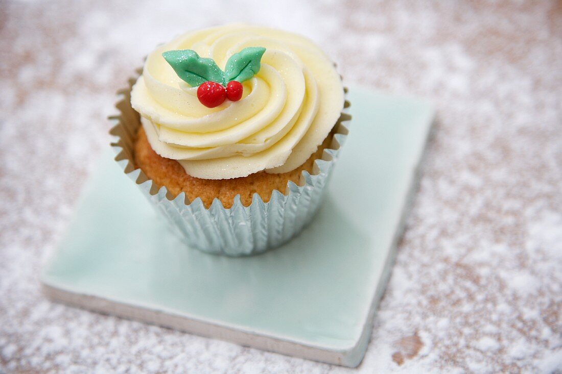 A cupcake decorated with light frosting and marzipan leaves