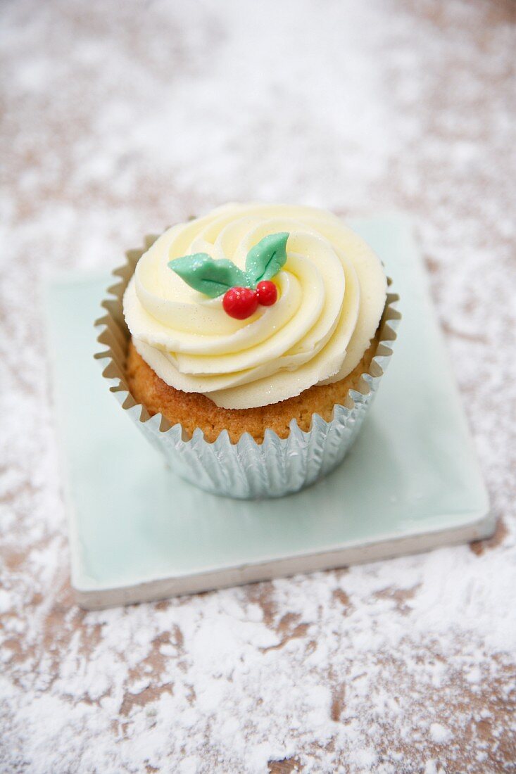 A cupcake decorated with light frosting and marzipan leaves