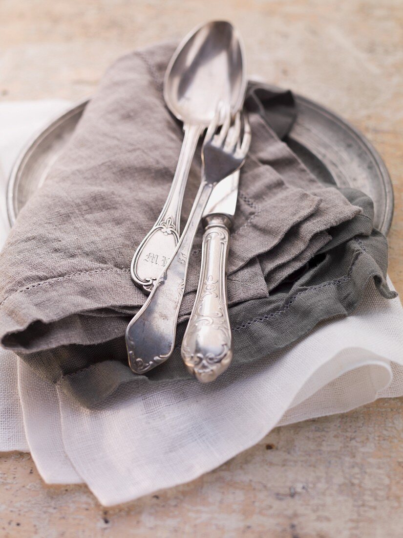 Cutlery on a linen napkin on a zinc plate