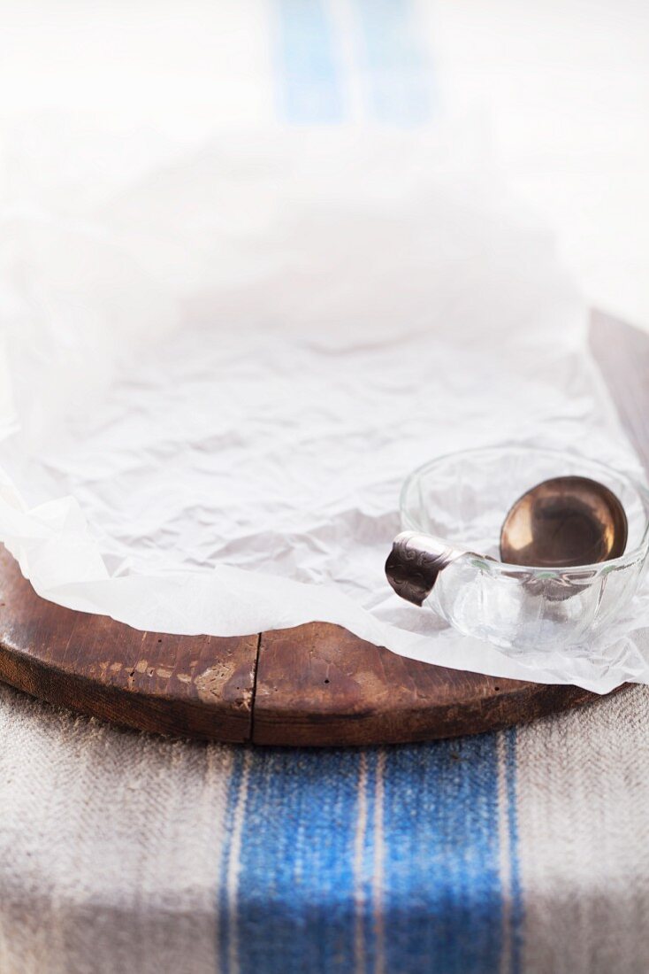 Baking paper, glass bowls and a silver spoon on a wooden bread