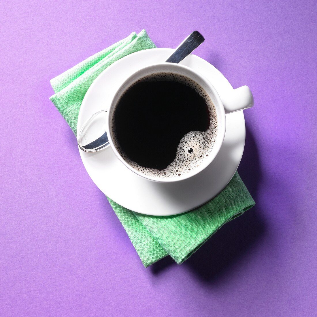 Tasse mit schwarzem Kaffee auf lila Untergrund