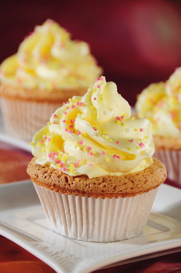 Cupcakes mit gelber Creme und Zuckerstreuseln