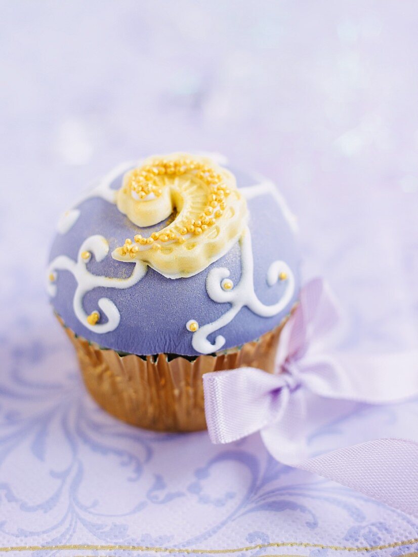 Festlich verzierter Cupcake mit lila Fondant